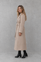 Women's elegant wrap coat in a longline design with a tailored lapel collar and adjustable matching waist belt, offering a flattering regular fit and lightweight warmth for autumn and winter wear.