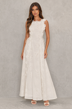 Woman wearing a white lace dress against a plain background