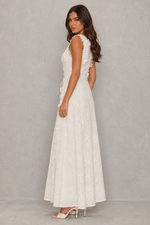 Woman wearing a white lace dress against a gray background
