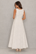 Woman wearing a white lace dress against a plain background