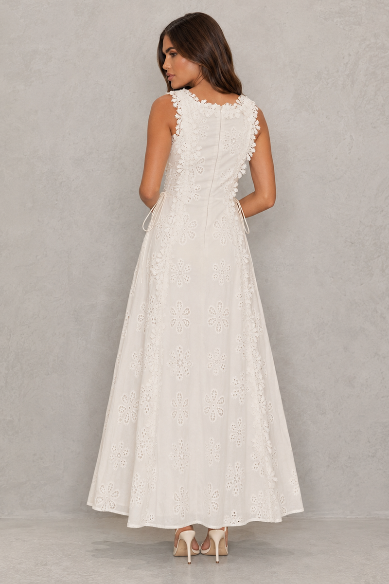 Woman wearing a white lace dress against a plain background
