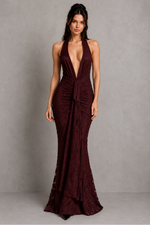 Woman wearing a burgundy evening gown against a gray background