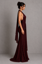 Woman wearing a burgundy evening gown against a gray background