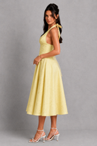 Woman wearing a yellow dress against a gray background
