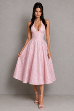 Woman wearing a pink lace dress against a gray background