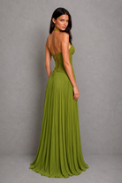 Woman wearing a green evening gown with a pleated skirt against a gray background