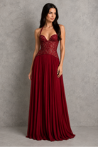Woman wearing a burgundy evening gown against a gray background