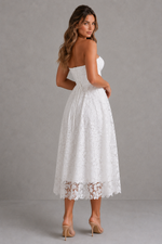Woman wearing a white lace dress against a gray background