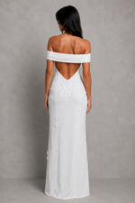 Woman wearing a white off-shoulder gown with floral details on a gray background