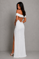 Woman wearing a white off-shoulder dress with a high slit on a gray background