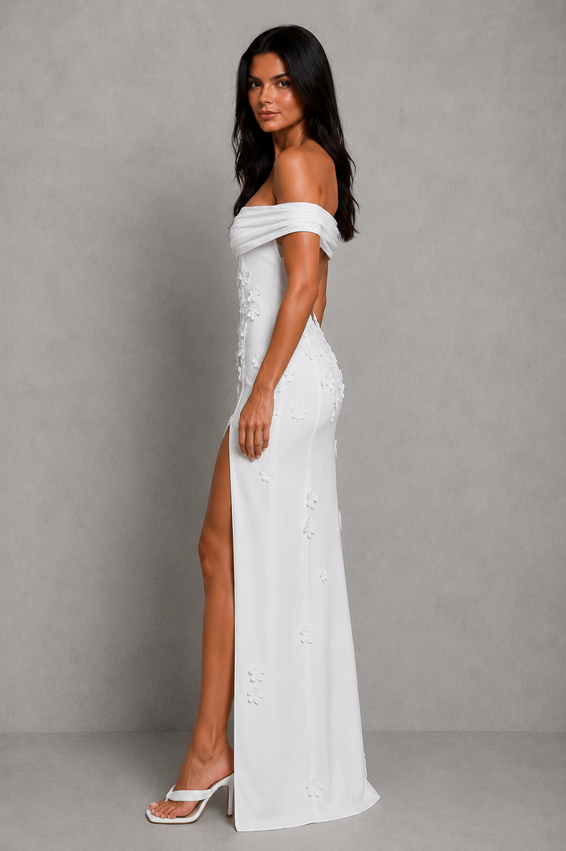 Woman wearing a white off-shoulder dress with a high slit on a gray background