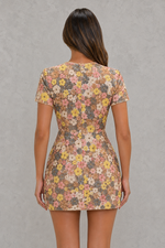 Woman wearing a floral dress against a gray background