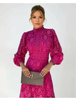 Woman wearing a pink lace dress holding a YSL handbag against a white background
