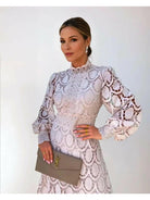 Woman wearing a white lace dress holding a YSL clutch against a white background
