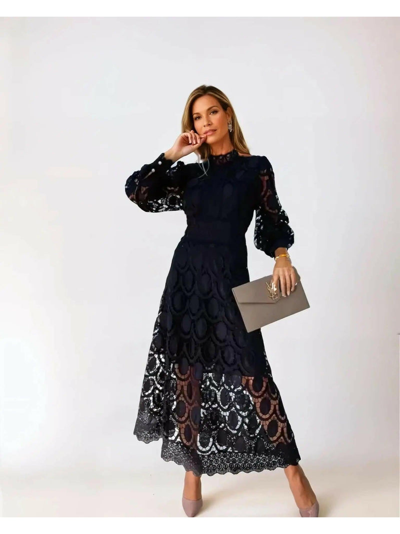 Woman wearing a black lace dress holding a clutch against a white background