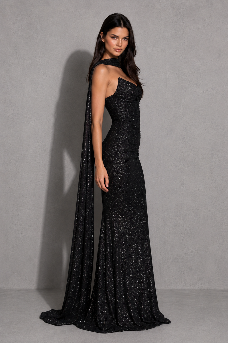 Woman wearing a black evening gown with a cape against a gray background