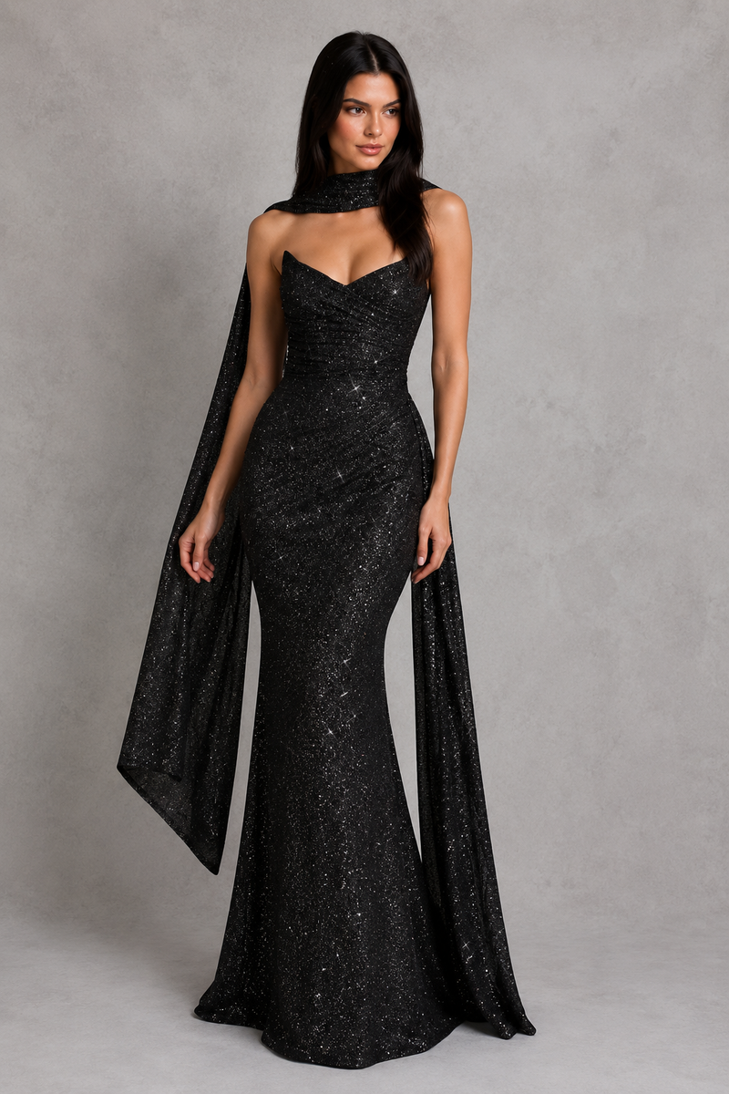Woman wearing a black sequin gown with a cape on a gray background