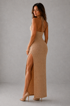 Woman wearing a beige dress with a high slit on a gray background