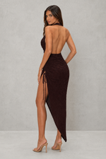Woman wearing a brown dress with a high slit on a gray background