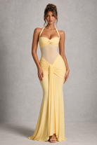 Woman wearing a yellow evening gown against a gray background