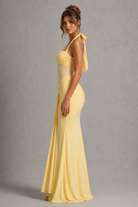 Woman wearing a yellow evening gown against a gray background