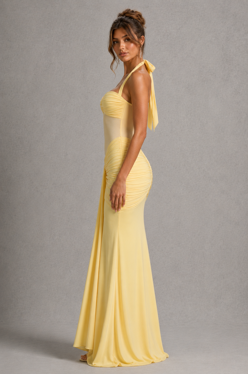 Woman wearing a yellow evening gown against a gray background