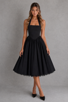 Woman wearing a black halter neck dress against a gray background
