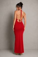 Woman wearing a red dress with cut-out back against a neutral background