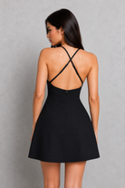 Woman wearing a black dress with thin straps on a gray background
