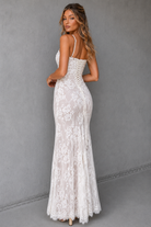 Woman wearing a white lace dress against a gray background