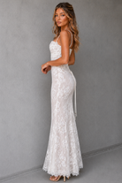 Woman wearing a white lace dress against a gray background