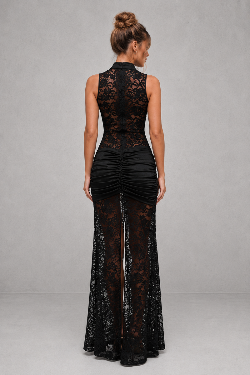 Woman wearing a black lace dress with a high slit on a gray background