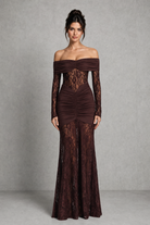 Woman wearing a brown lace off-shoulder gown against a gray background