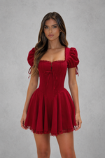 Woman wearing a red dress with puff sleeves against a gray background