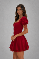 Woman wearing a red dress with puff sleeves against a gray background