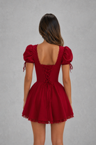 Red dress with puff sleeves and lace-up back on a gray background