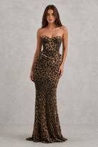 Woman wearing a strapless leopard print gown against a gray background