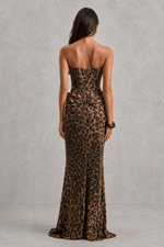 Woman wearing a strapless leopard print gown against a gray background