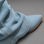 Women’s light blue denim knee-high boots with ruched shafts, pointed toes and square block heels.