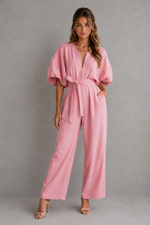 Woman wearing a pink jumpsuit against a gray background