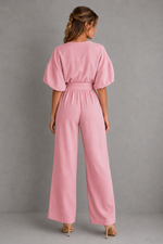 Woman wearing a pink jumpsuit against a gray background