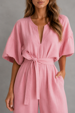 Pink jumpsuit worn by a model against a gray background