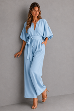 Woman wearing a light blue jumpsuit against a gray background