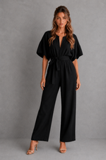 Woman wearing a black jumpsuit against a gray background