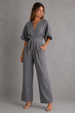 Woman wearing a gray jumpsuit against a plain background