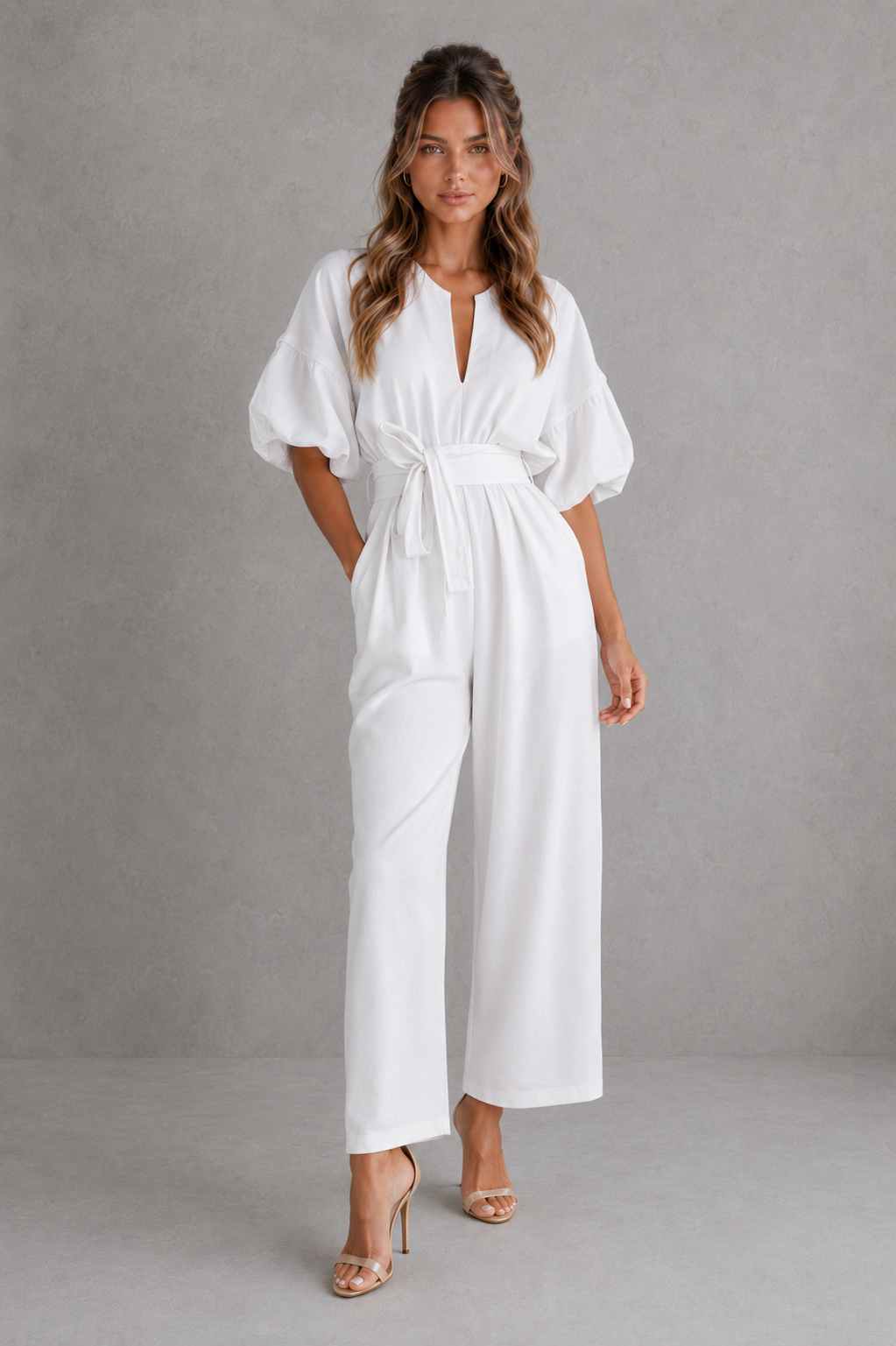Woman wearing a white jumpsuit against a gray background