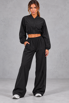 Women's black cropped zip-up jacket and wide leg trouser fitness set – front view
