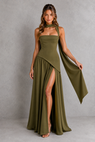 Woman wearing a green evening gown with a slit on a gray background