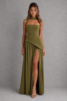 Woman wearing a green dress with a slit on a gray background