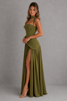 Woman wearing a green dress with a slit on a gray background